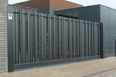 a large metal gate on the side of a brick building next to a parking meter