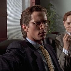 two men in suits and ties are talking on the phone