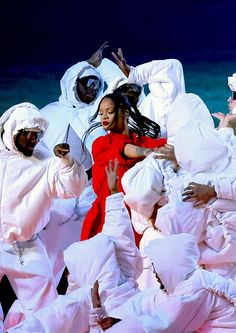 a group of people dressed in white performing on stage with one woman holding up her arms