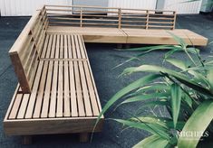 a wooden bench sitting on top of a cement ground next to a potted plant