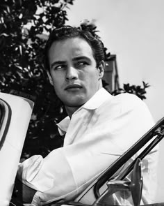 a black and white photo of a man sitting in a car