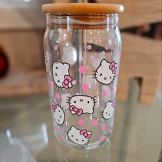 a glass with hello kitty decals on it sitting on a table next to a wooden handle