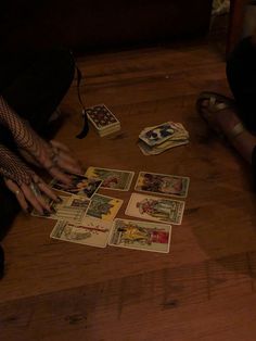 a person sitting on the floor playing cards with their legs crossed and one hand in front of them