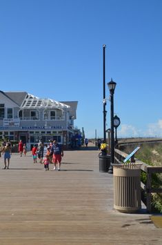 people walking on a boardwalk near the ocean