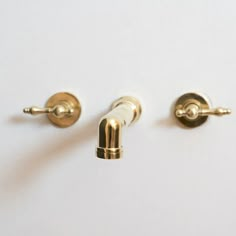 two gold colored handles on the back of a white wall