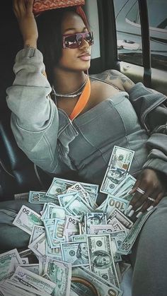 a woman sitting in the back seat of a car with lots of money