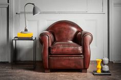 a brown leather chair sitting in front of a white wall