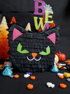 a black cat made out of paper surrounded by candy