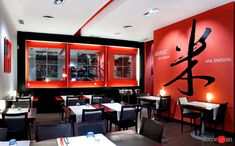 the interior of a restaurant with red walls and black tables, chairs, and windows