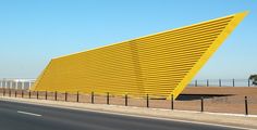 a large yellow structure sitting on the side of a road next to a fenced in area