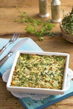 a casserole dish with broccoli and cheese in it on a blue napkin