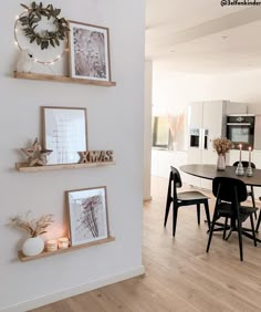 a dining room table with chairs and pictures on the wall above it, along with candles