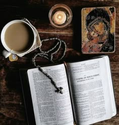 an open book sitting on top of a wooden table next to a candle