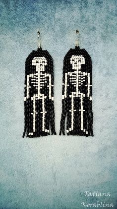 pair of black and white beaded earrings with skeleton silhouettes on the front side