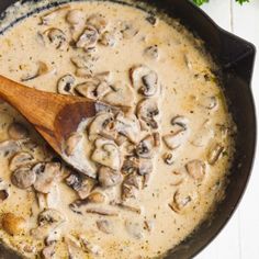 a wooden spoon in a skillet filled with mushroom gravy and parsley