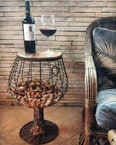 a glass of wine sitting on top of a table next to a wicker chair