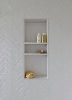 a white shelf with some items on it in a room that is decorated with herringbone tile