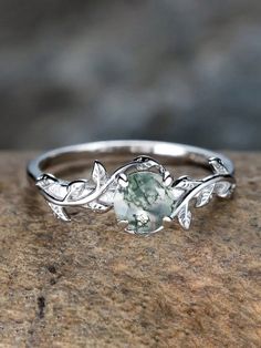 a ring with leaves on it sitting on top of a stone surface and surrounded by stones