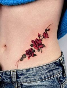 a woman's stomach with red flowers on it and leaves growing out of the side