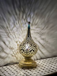 a decorative lamp sitting on top of a table next to a white wall with shadows