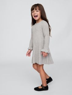 Supersoft ribbed knit sweater dress.  Crewneck.  Long sleeves with ruffle cuffs.  Godet styling at skirt.  This product was made in a factory that runs the Gap Inc.  P. A. C. E.  Personal Advancement & Career Enhancement) program.  P. A. C. E.  is our educational program that helps the women who make our clothes build the skills, knowledge, confidence & resilience needed to advance in work & life.  Learn more here.  Fit and flare silhouette.  Hits at the knee.  Sizes range from baby to toddler. Girls Designer Dresses, Kids Robes, Rib Sweater, Knitted Design, Kids Jumpers, Jersey Knit Dress, Ribbed Sweater Dress, Kids Designer Dresses, Dress Pleated