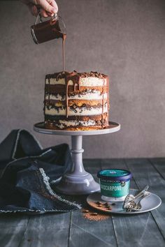 someone pouring chocolate sauce on top of a cake