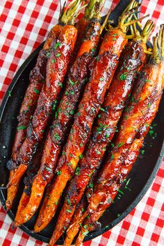 some carrots are on a black plate with red and white checkered table cloth