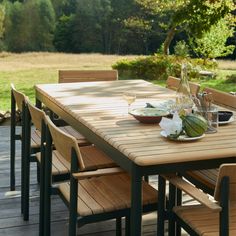 a wooden table with chairs and plates on it in the middle of a patio area