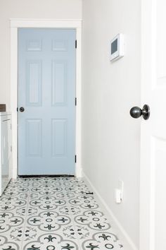 a blue door in a white room next to a washer and dryer