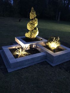 an outdoor sculpture with lights in the shape of trees and bushes on top of cement blocks