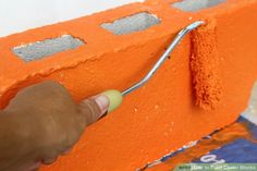 someone is painting an orange brick with white paint