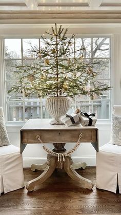 a christmas tree is in the center of a room with two chairs and a table