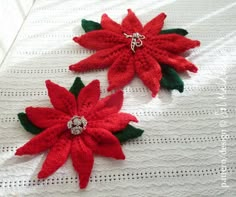 two red poinsettis are sitting on a white tablecloth with green leaves