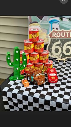 a table topped with lots of food next to a green cacti and some toy cars