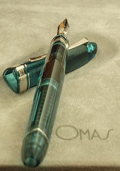 a fountain pen laying on top of a white sheet with the word omo written across it