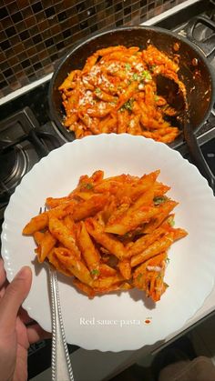 a white plate topped with pasta next to a frying pan filled with other food