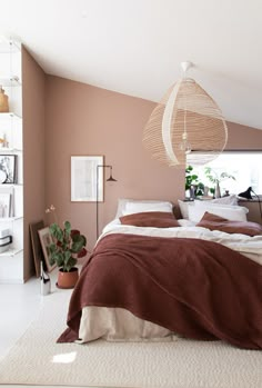 a bedroom with a bed, plant and hanging light fixture in the middle of it