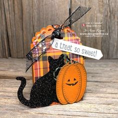 a black cat sitting on top of a wooden table next to a trick box with a jack - o'- lantern