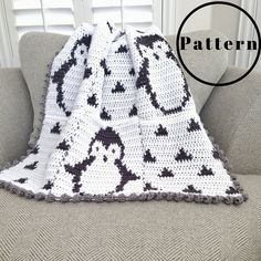 a white and black crocheted blanket sitting on top of a couch next to a window