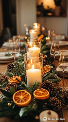 a table with candles, orange slices and pineconis on it is set for a festive dinner