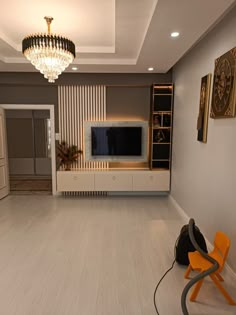 a living room with white walls and wood flooring has a chandelier hanging from the ceiling