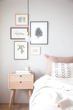 a white bed sitting next to a wooden table with pictures on the wall above it