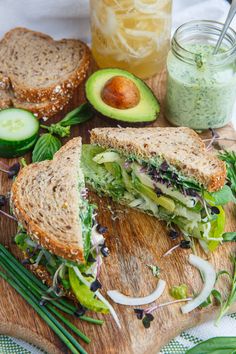 a sandwich cut in half sitting on top of a cutting board next to sliced cucumbers