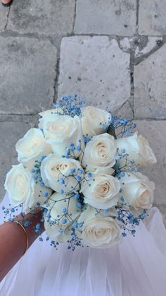 a bride's bouquet with white roses and baby's breath is held in her hand