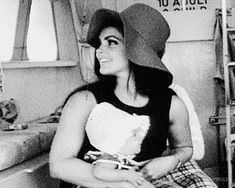 a black and white photo of a woman wearing a hat sitting in a room with bunk beds