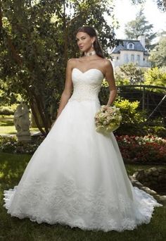 a beautiful woman in a wedding dress posing for a photo on the grass with her bouquet