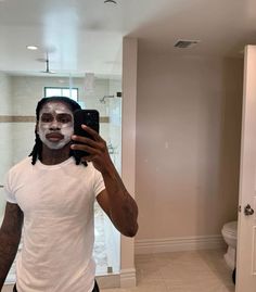 a man taking a selfie in the bathroom with his face painted white and black