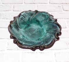 a green bowl sitting on top of a white brick wall