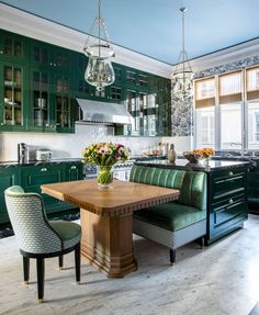 a kitchen with green cabinetry and an island in the middle, surrounded by chairs