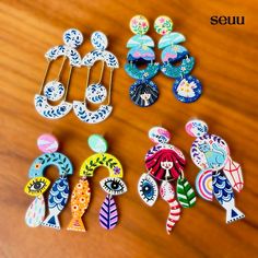 several pairs of colorful earrings sitting on top of a wooden table